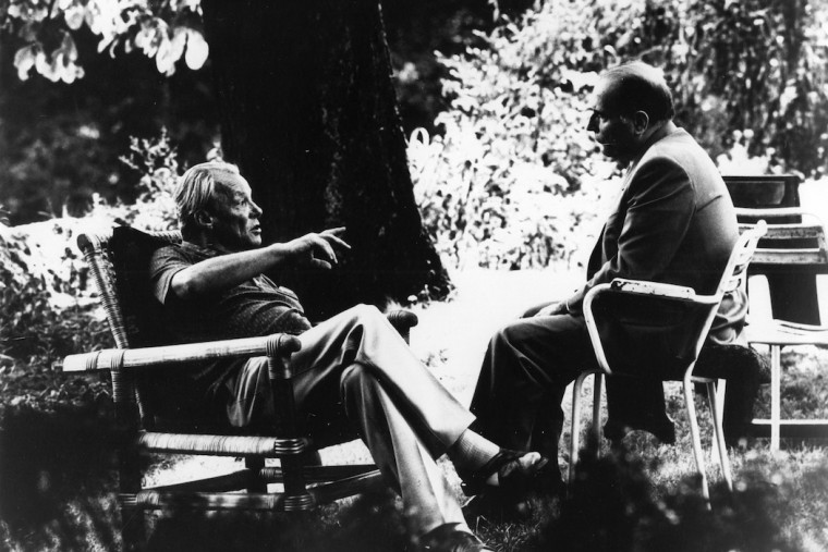 Schwarz-Weiß-Aufnahme von Willy Brandt und François Mitterrand. Beide sitzen sich im Garten auf Stühlen gegenüber und sprechen miteinander.