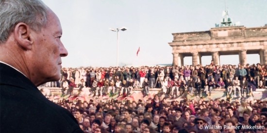 Willy Brandt blickt am Tag nach der Öffnung der Berliner Mauer auf Menschenmassen, die vor und auf der Berliner Mauer stehen und sitzen. Öffnet den multimedialen Zeitstrahl der Jahre von 1983 bis 1992.